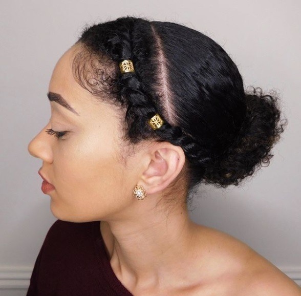 Protective hairstyles: Woman with natural hair in a low bun puff style with braided bangs