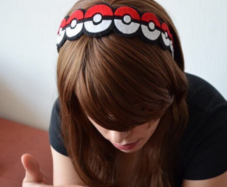 woman with her head bowed showing off her pokemon ball headband in her chocolate brown hair