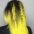 back view of a woman with bright yellow ombre hair with dark roots and two braids
