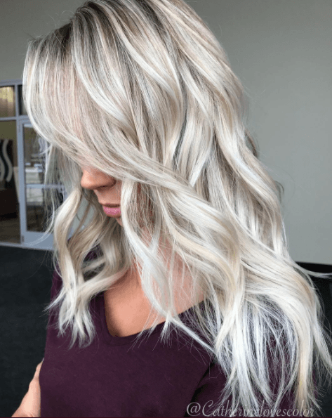 Shades of blonde hair: Woman with long wavy ice white hair wearing a black top.