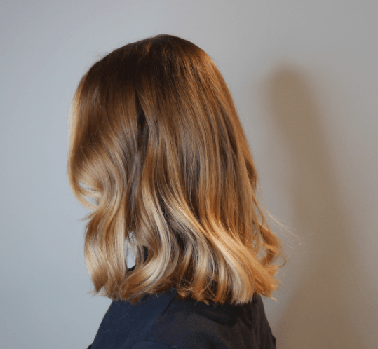 side view of a woman's shoulder length hair with waves and different shades of blonde