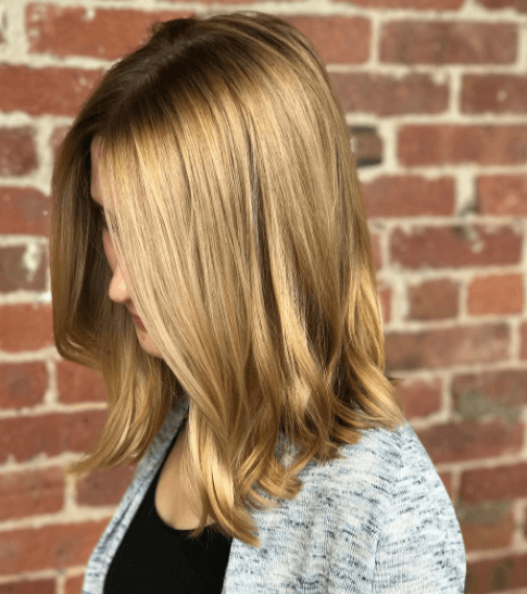 Shades of blonde hair: Woman with toffee blonde shoulder length hair with a slight wave.