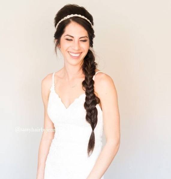 Wedding hairstyles for long hair: Smiling bride with long brunette hair in a side braid with voluminous roots and a headband