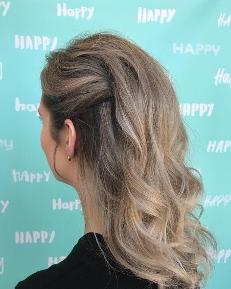 Wedding hairstyles for long hair: Woman with light brown hair in a half clipped up updo with curly lengths