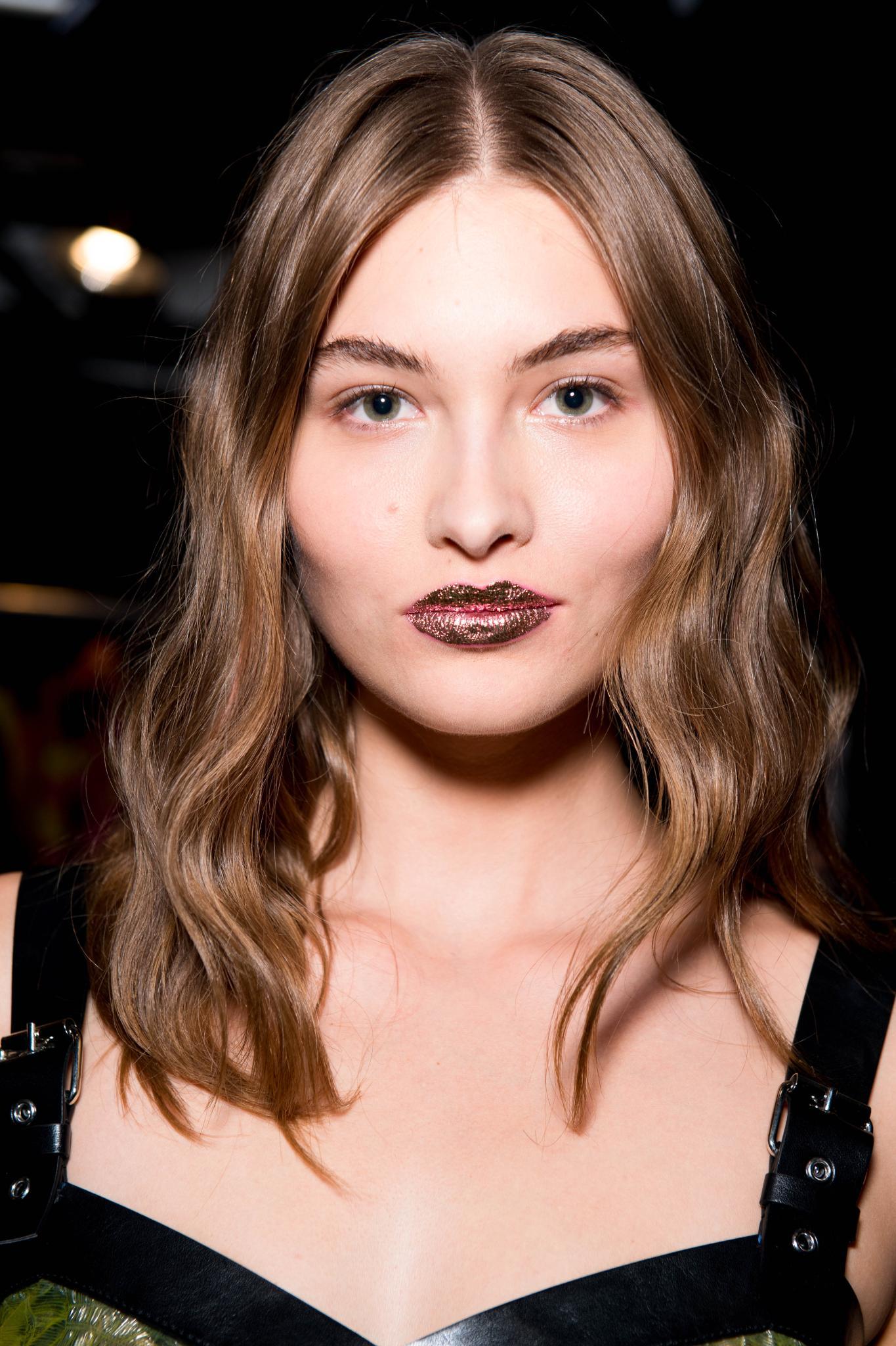 Hair glossing treatment: Woman with wavy shiny brown hair at Jermey Scott show with glitter lipstick