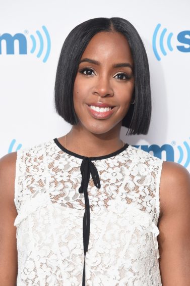 close up shot of kelly rowland with sleek chin length bob hair, wearing white top and posing on the red carpet