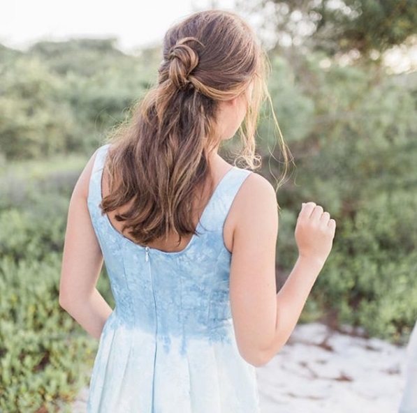 Wedding hairstyles for long hair: Back view of a woman with medium-long curly light brown hair in a half-up half-down knot hairstyle