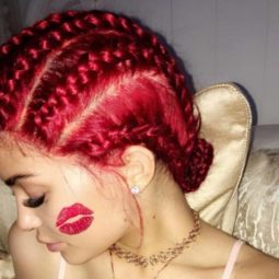 Kylie Jenner's red hair with cornrows posing to the side with a kiss of red lipstick on her cheek