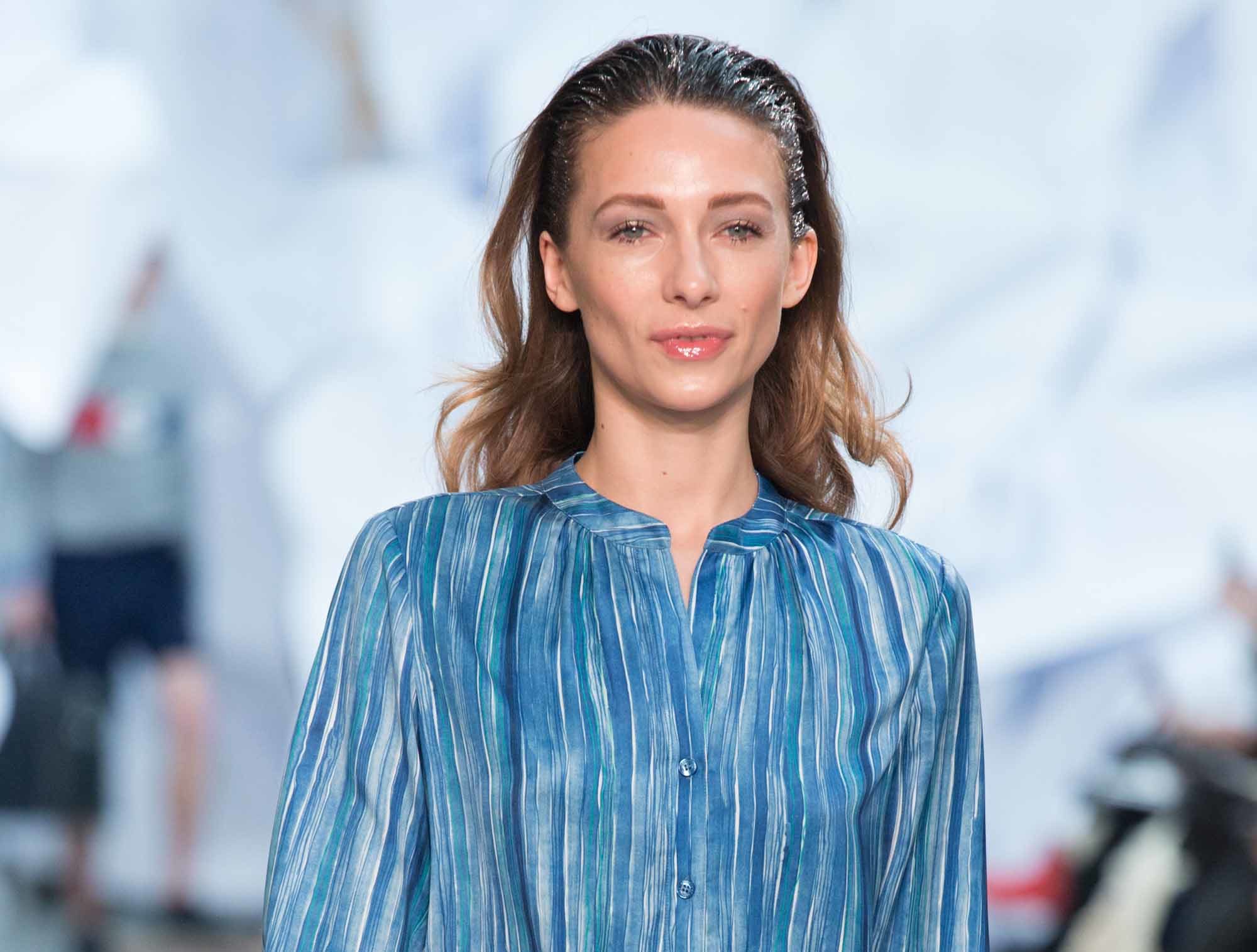 woman with dark blonde wavy hair with pushed back wet look roots wearing stripe blue shirt at aw16 fashion week show