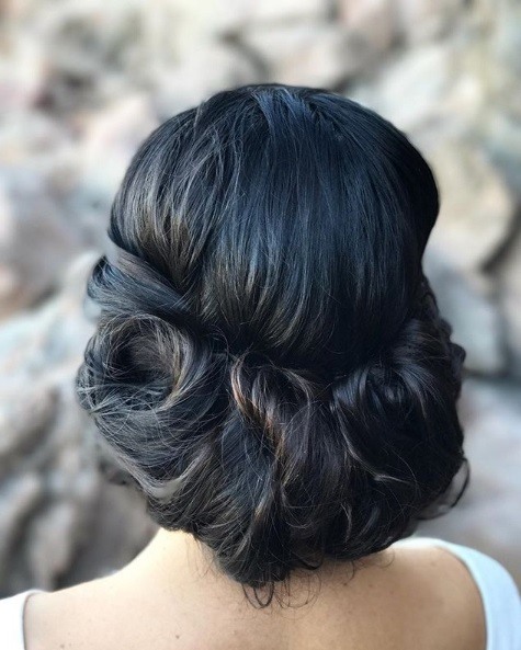 Wedding hairstyles for long hair: Back view of a woman with dark brown almost black hair in a low pinned updo style