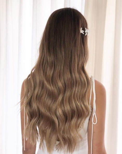 Wedding hairstyles for long hair: Back view of a woman with soft ash brown hair in subtle waves with a sparkly barrette