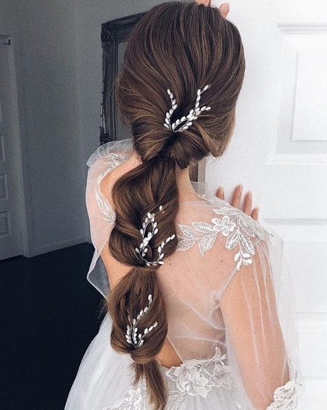 Wedding hairstyles for long hair: Back view of a brunette woman with waist-length hair in a bridal topsy turvy ponytail style
