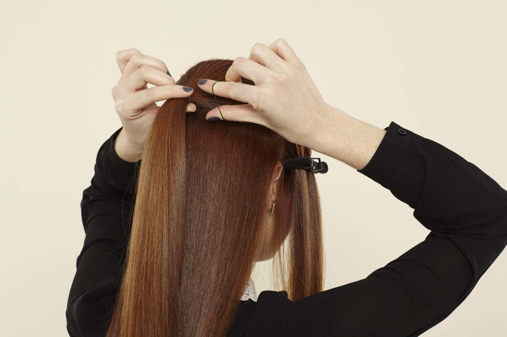 a woman tying up her long brunette hair