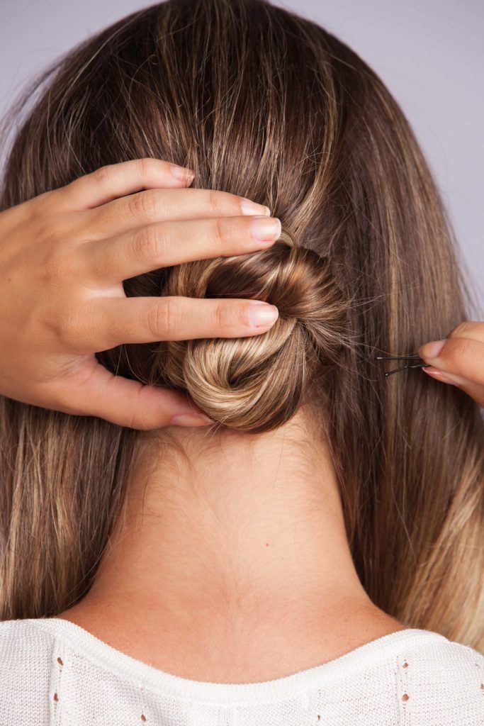 a woman making a twisted bun