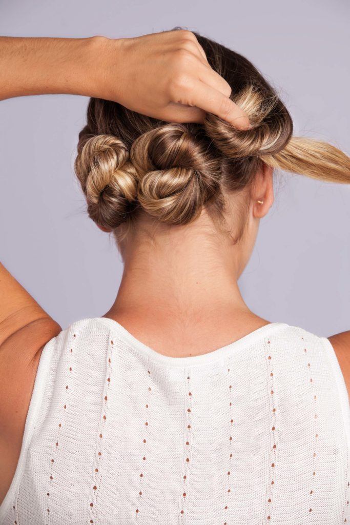 a woman making twisted bun hair