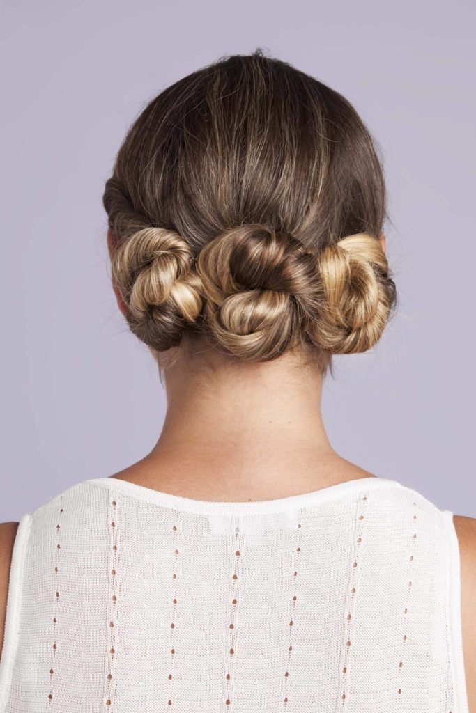 a rear view of twisted bun woman on the purple background