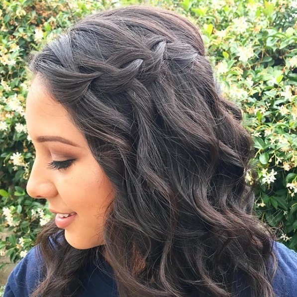 Wedding hairstyles for long hair: Close-up shot of a woman with curled dark hair in a waterfall braid