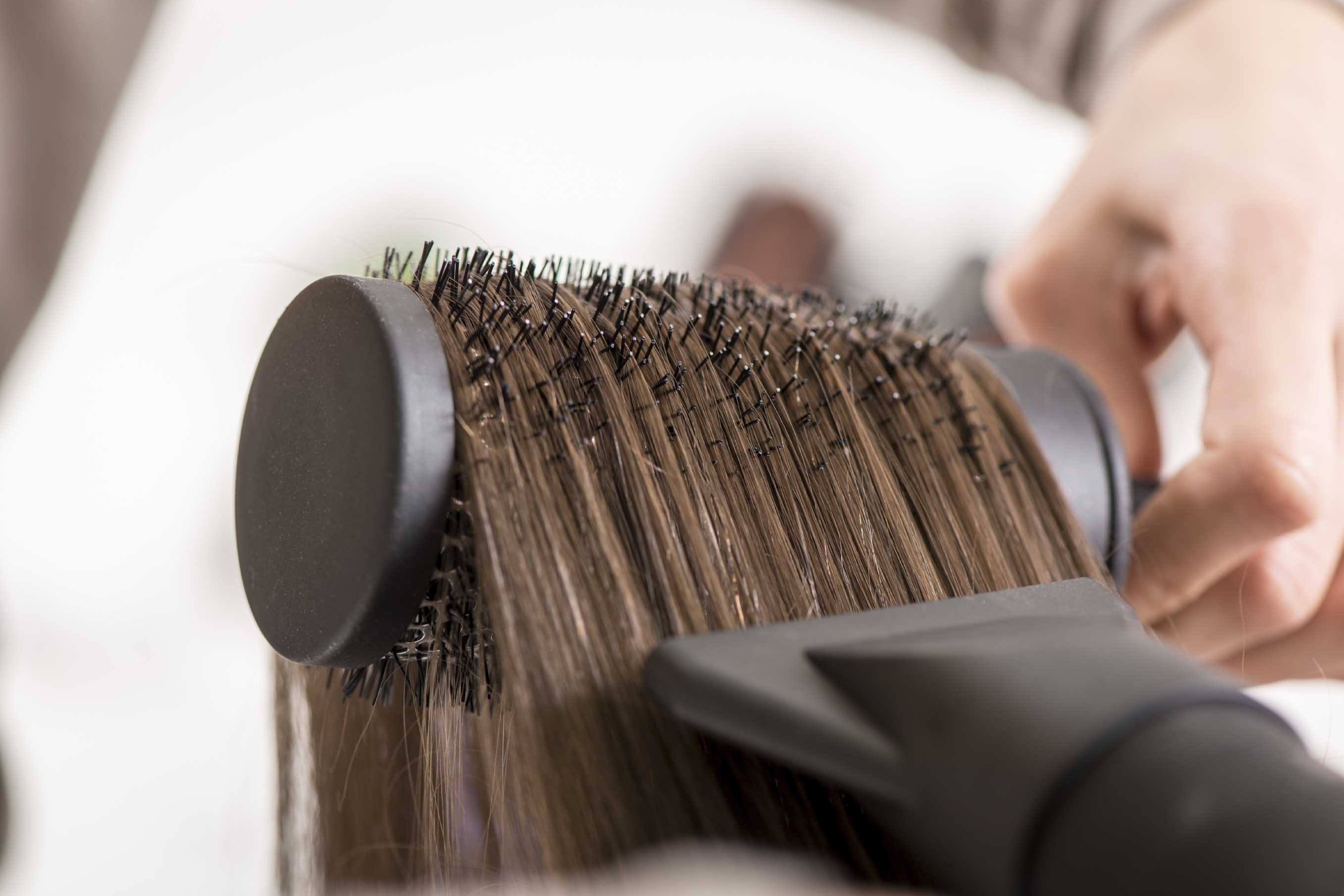 Close-up of a drying brown hair with hair dryer and round brush