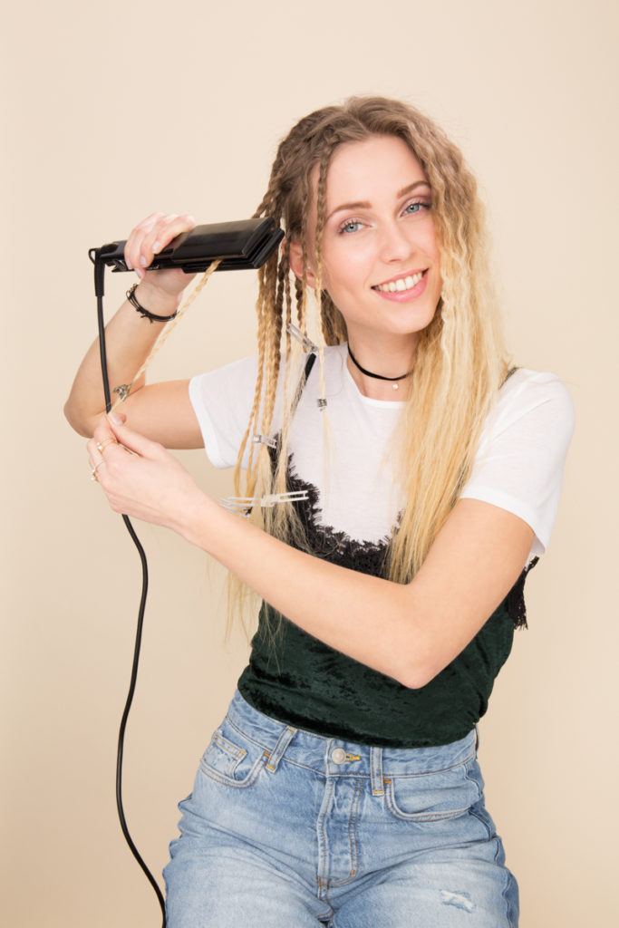 Crimped hair tutorial: Blonde model using a straightener on her braids