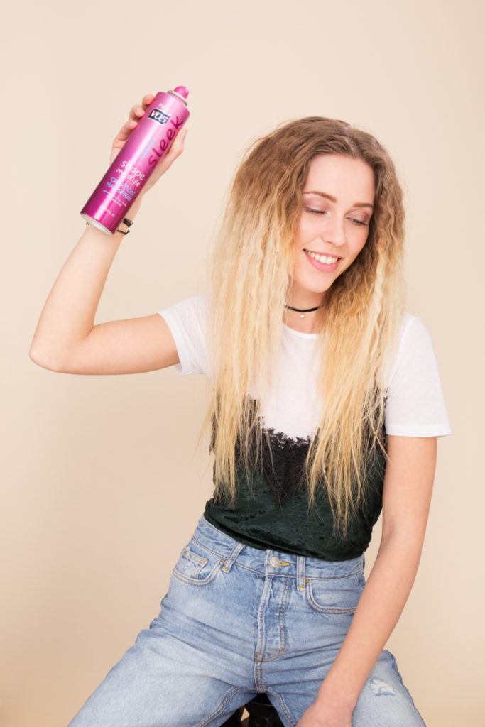 blonde model spraying crimped hair with VO5 Creation Hairspray