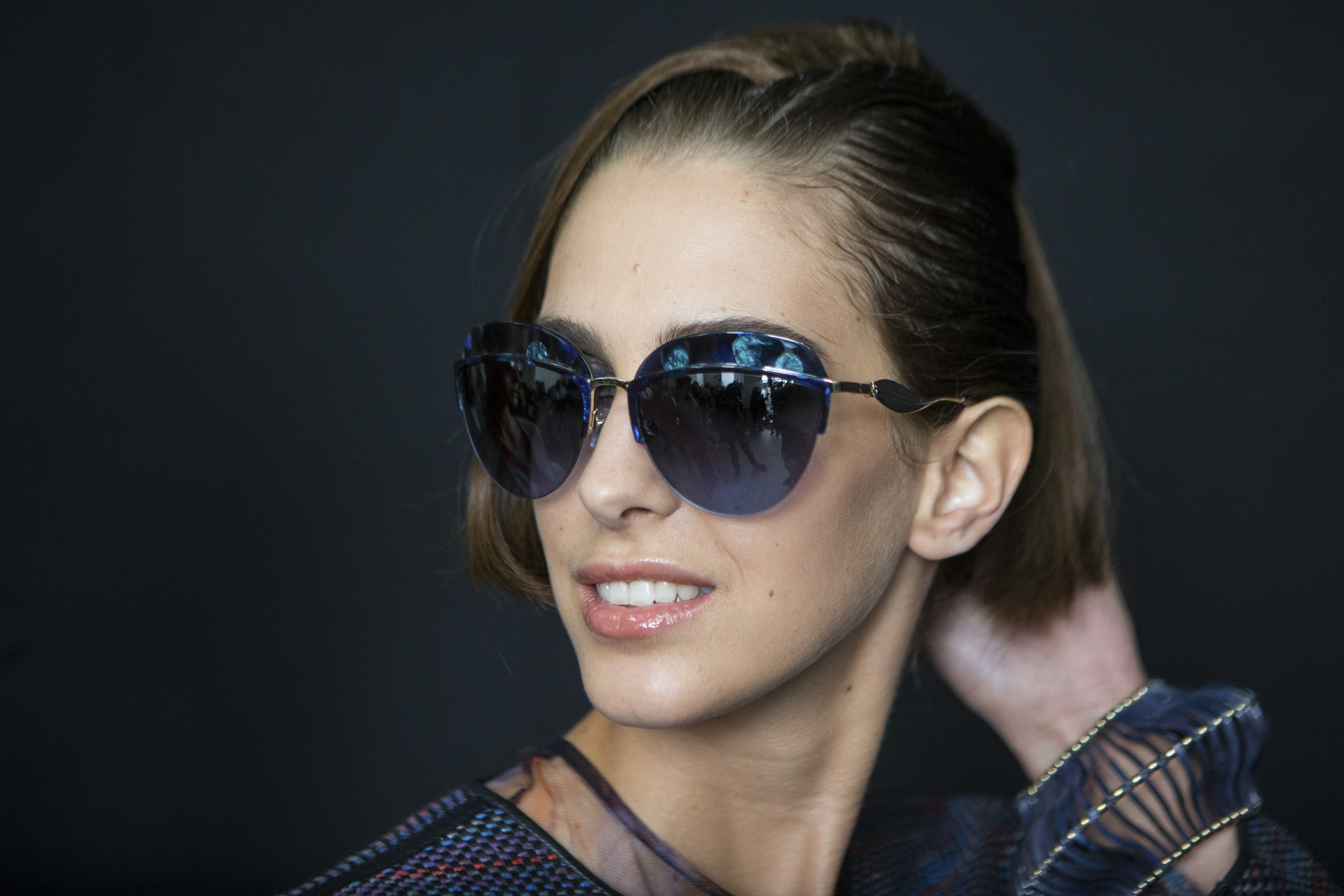 close up shot of model backstage at giorgio armani with faux bob hairstyles, wearing big sunglasses and blue top