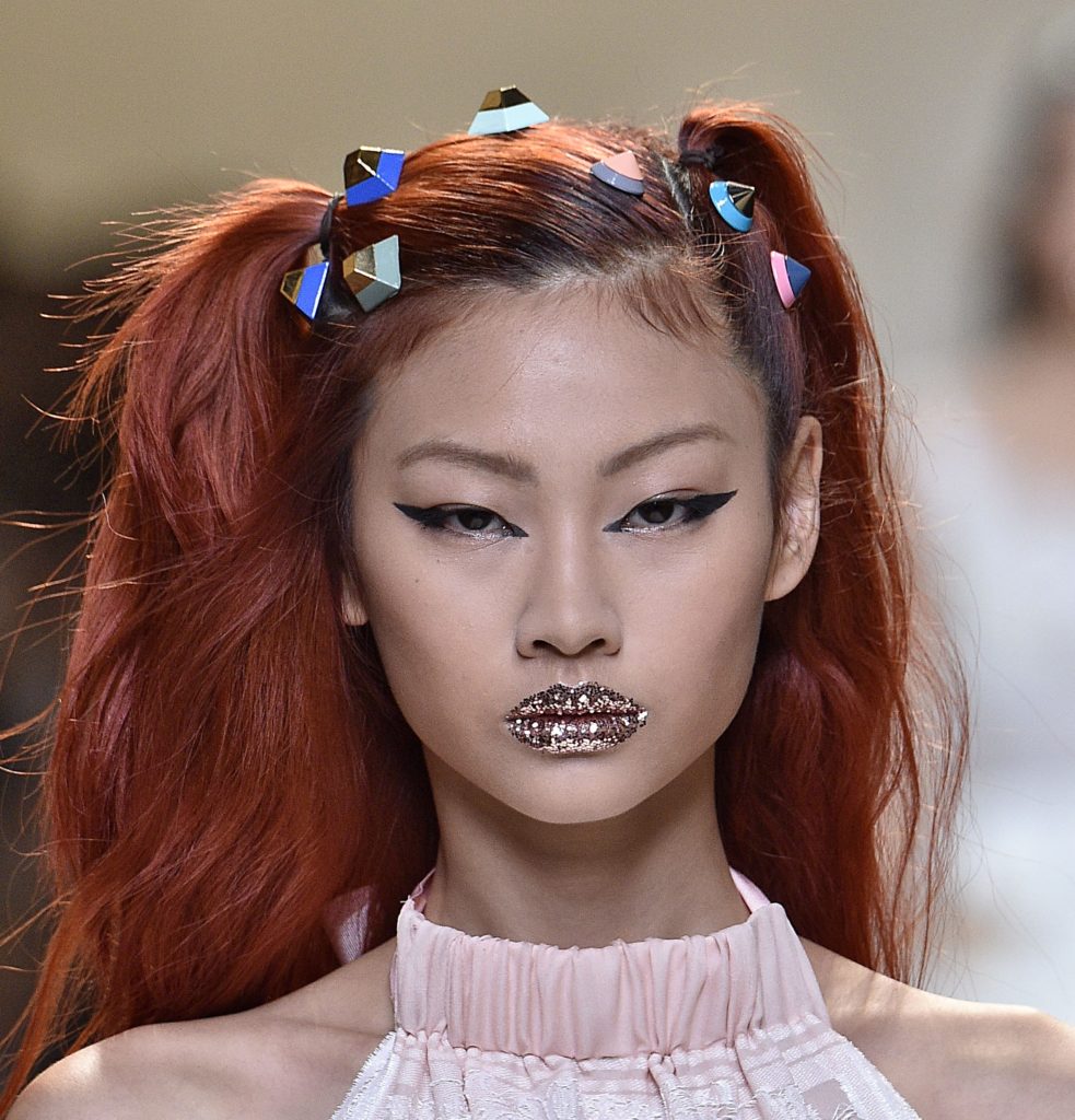 model on the Fendi SS17 runway with dyed red hair worn in pigtails with candy look accessories attached and glitter lips
