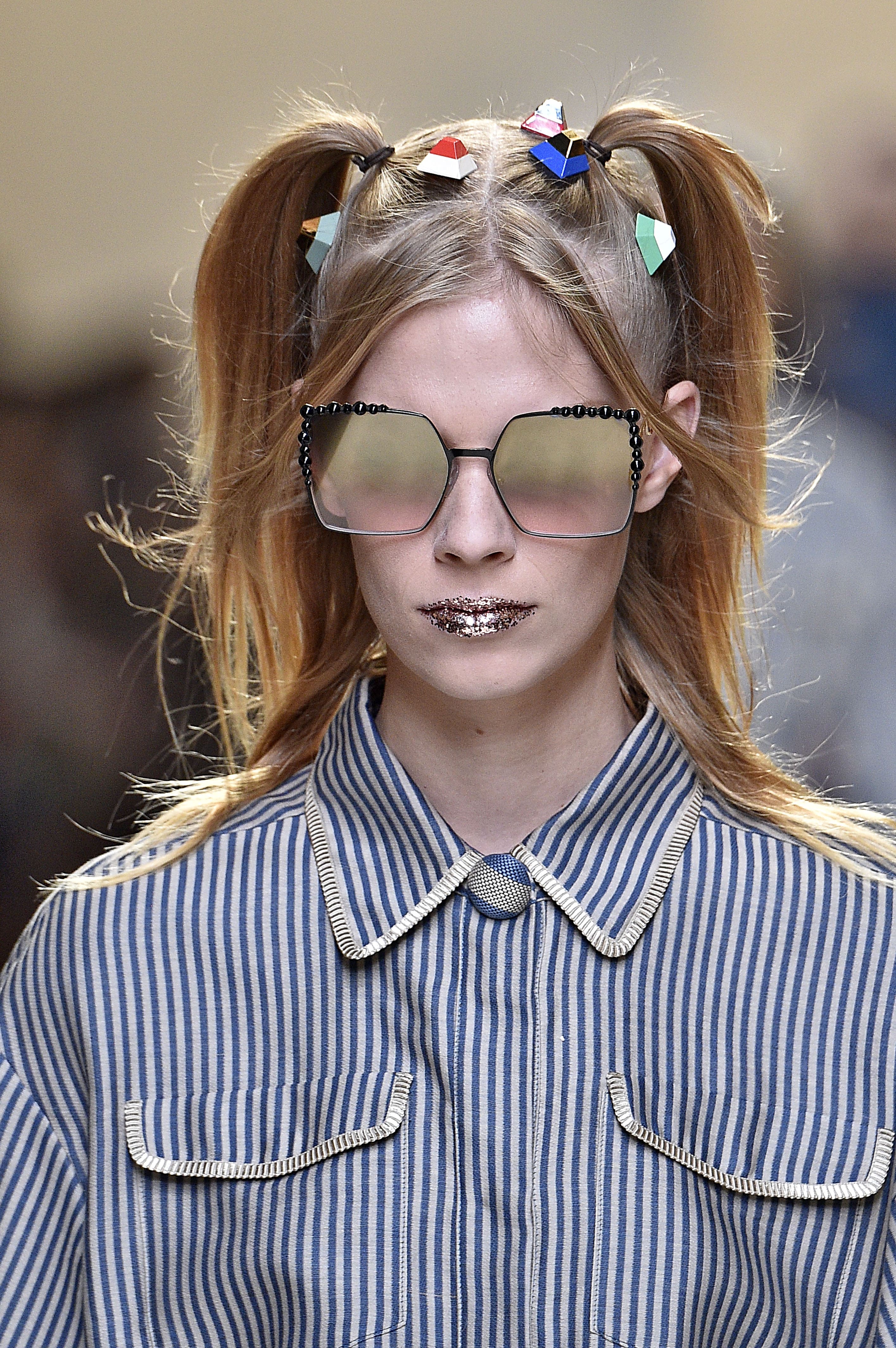 model on the Fendi SS17 runway with blonde hair worn in pigtails with candy look accessories attached and glitter lips wearing a striped outfit