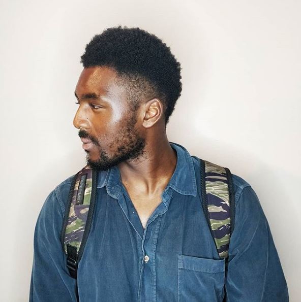 A young black man turning to the side with a South of France hairstyle