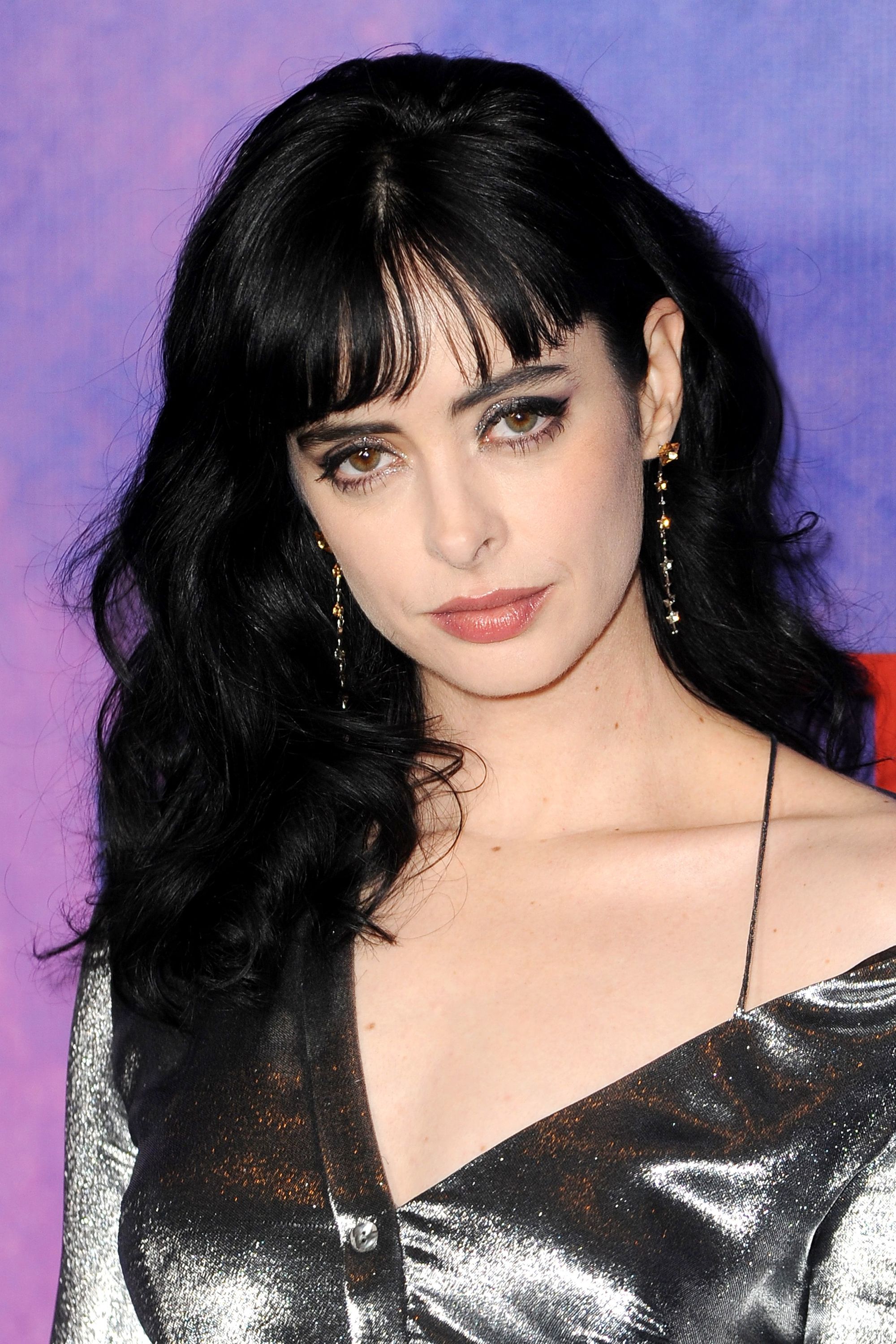 Medium hairstyles for thick hair: Krysten Ritter with mid-length dark brown wavy hair with bangs