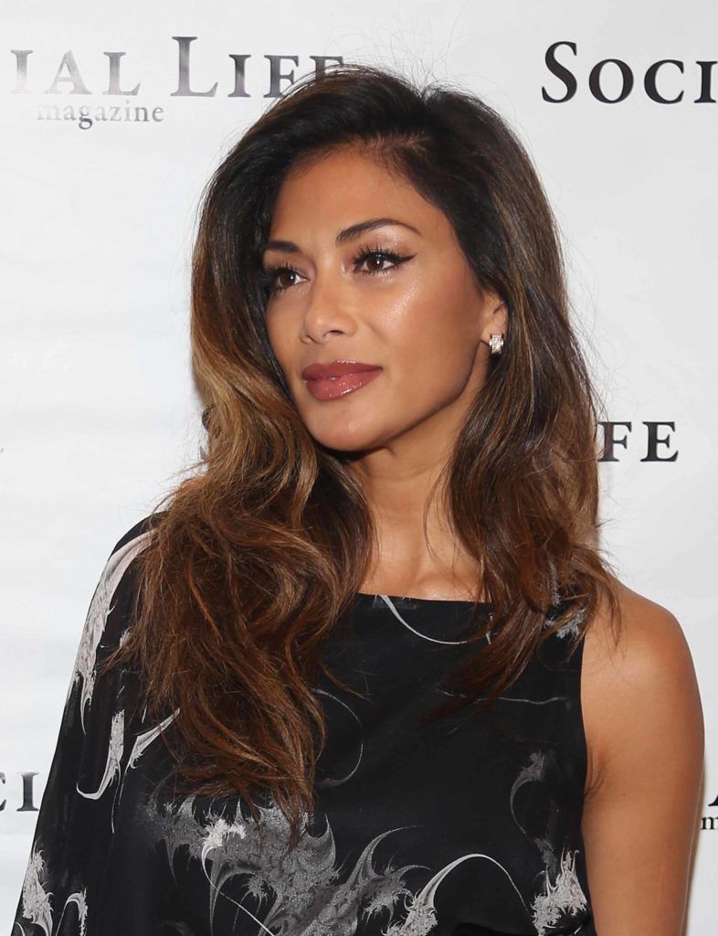 Nicole Scherzinger at industry event with long caramel balayage hair wearing one sleeve black patterned dress
