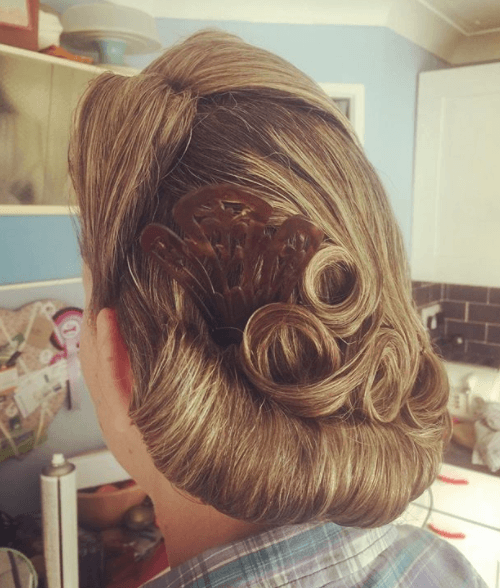 Gibson girl hair: Back view of a woman with her hair up in victory rolls and a gibson tuck