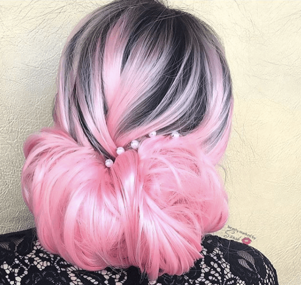 Gibson girl hair: Back view of a woman with pink and black hair in a loose gibson tuck hairstyle with pearl accessories