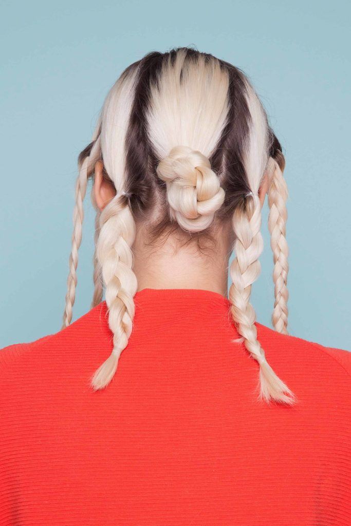 Snake braid hairstyles: back view of blonde owman with a braided bun and two braids either side mid way through snake braid hair tutorial.