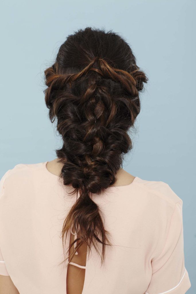 back shot of a woman with long brunette in a mermaid braid wearing a pink top