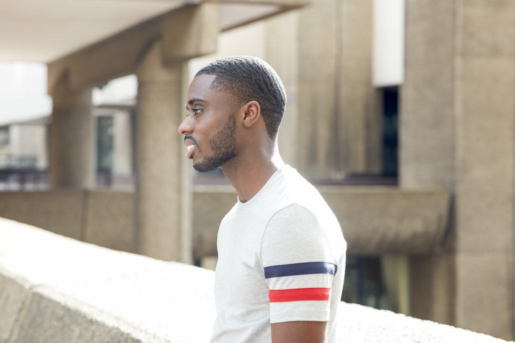 360 waves: Man with short afro hair in 360 waves with facial hair wearing a grey t-shirt, standing outside