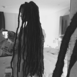 Rihanna taking a black and white selfie in the mirror showing off her dreadlock extensions wearing a long white shirt