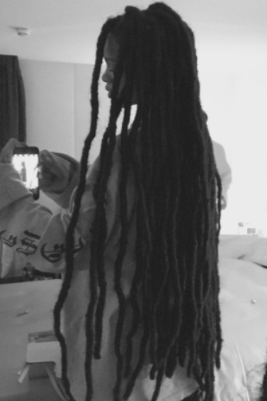 Rihanna taking a black and white selfie in the mirror showing off her dreadlock extensions wearing a long white shirt