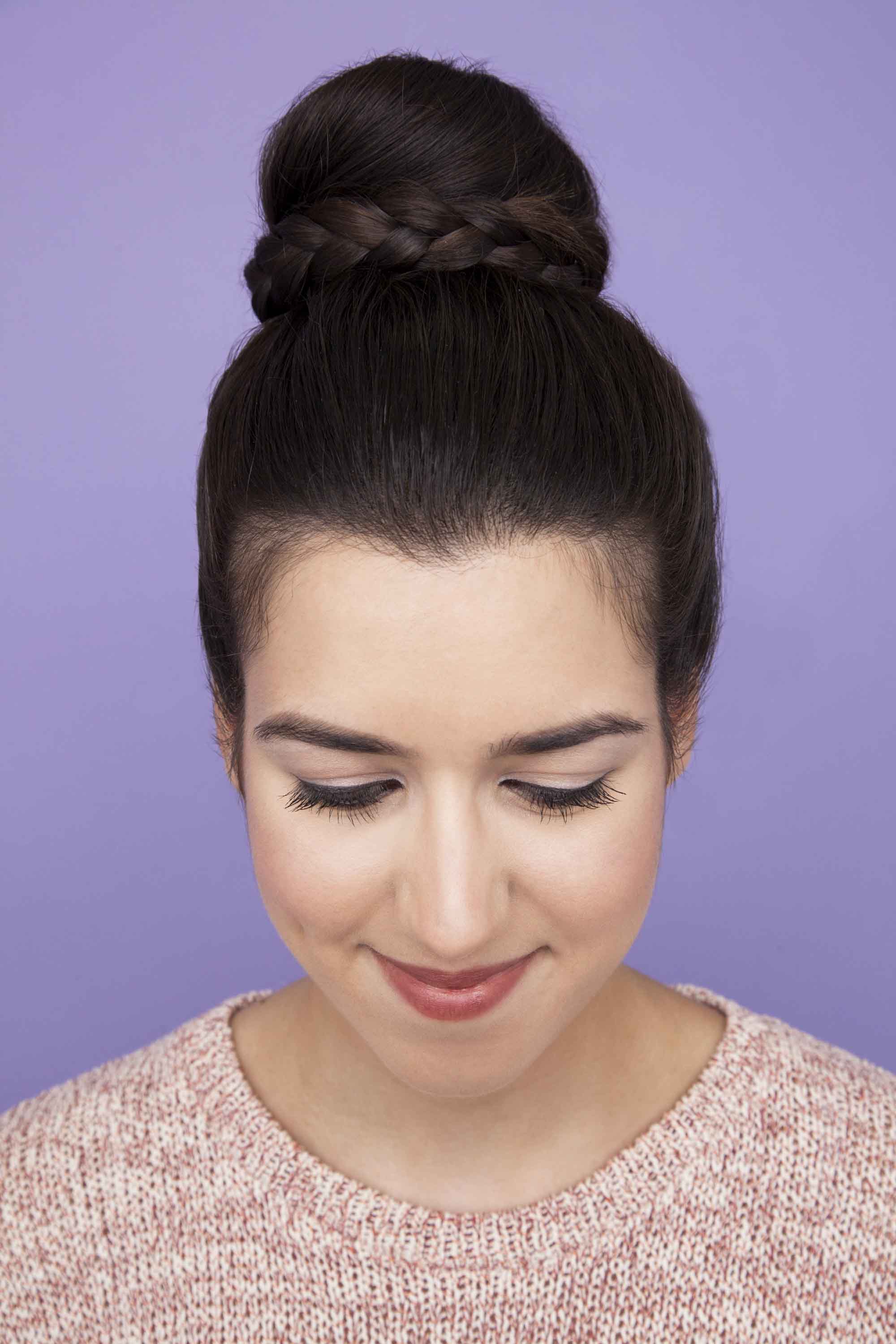 Easy updos - Braided ballerina bun on dark-haired model against a purple backdrop