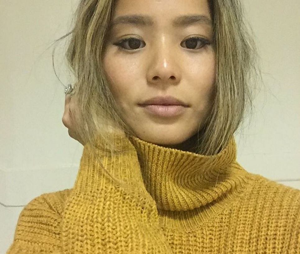 actress Jamie Chung taking a selfie wearing a chunky yellow turtle neck sweater with ash blonde hair tucked inside