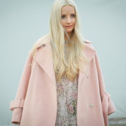 Purple shampoo: Blogger at fashion week with long light blonde blow-dried hair wearing a baby pink overcoat
