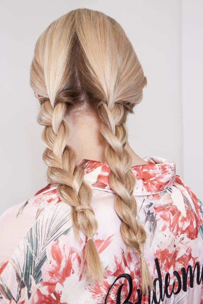 wedding chignon: blonde model with her hair in two pigtail braids wearing a floral bridesmaid robe