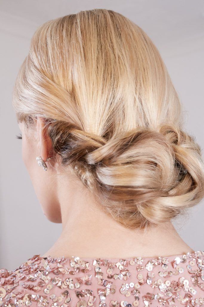wedding chignon: close up back view of a blonde model with her hair in a braided chignon
