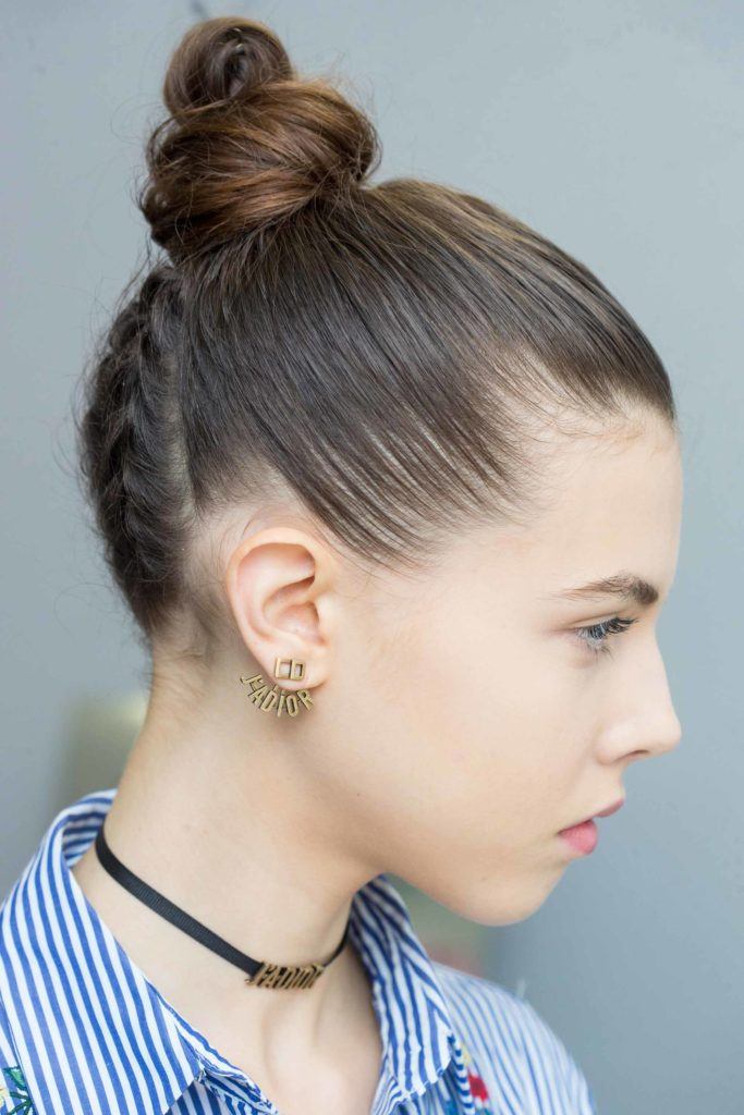 model with dark brunette hair with a braided knot wearing a striped blue shirt wearing dior earrings for the Christian Dior SS17 show