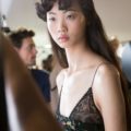 asian model backstage at the rochas ss17 paris fashion week show wearing a black lace top with long wavy dark hair and a curled fringe