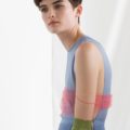 brunette model wearing a light blue dress with pink shiffon wrap and green gloves with short hair backstage at the rochas ss17 show with a curly pixie cut with bangs