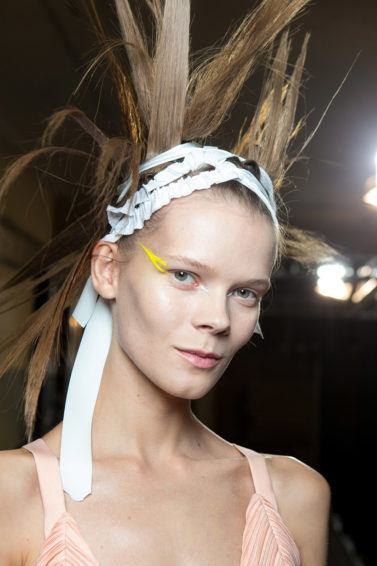 model backstage at the Haider Ackermann SS17 show with extreme spiky hair with a bandage wrapped around her head with a wing of colourful eyeliner
