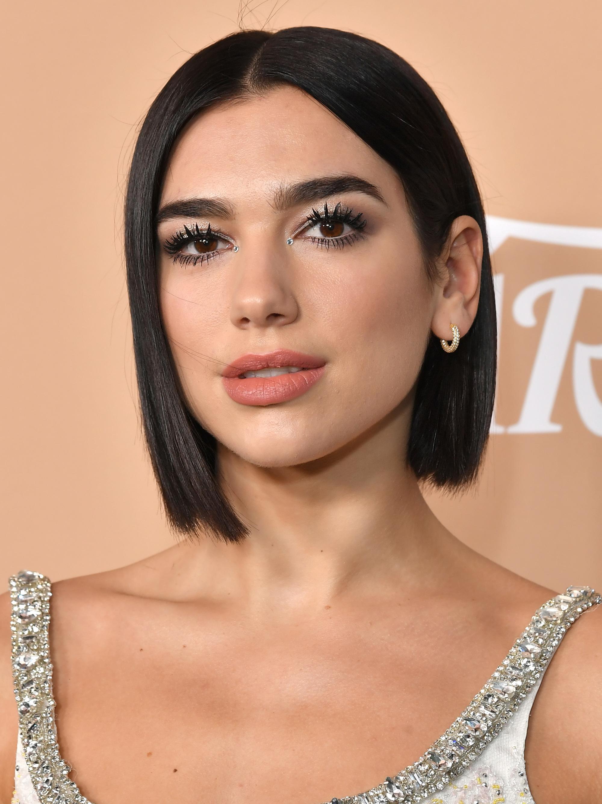 Haircuts for fine hair: Dua Lipa with a blunt dark brown bob, wearing a silver dress on the red carpet