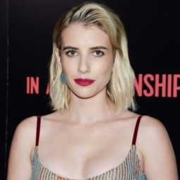 Emma Roberts with platinum blonde textured long bob, styled to the side, wearing glittery dress and red lipstick on the red carpet