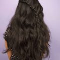 Divali hairstyles: Back view of a woman with long dark brown wavy hair in a half up half down diagonal braid