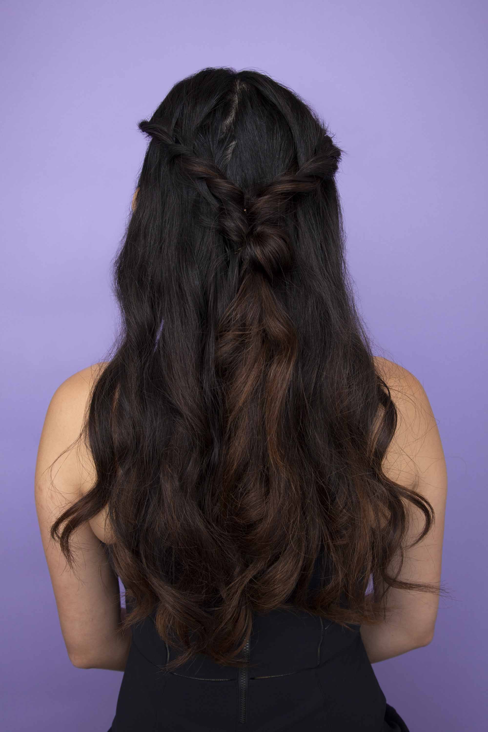 Diwali hairstyles: Back view of a woman with long dark hair wearing a half up half down twist hairstyle